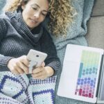 curly woman with gray sweater lying on brown sofa