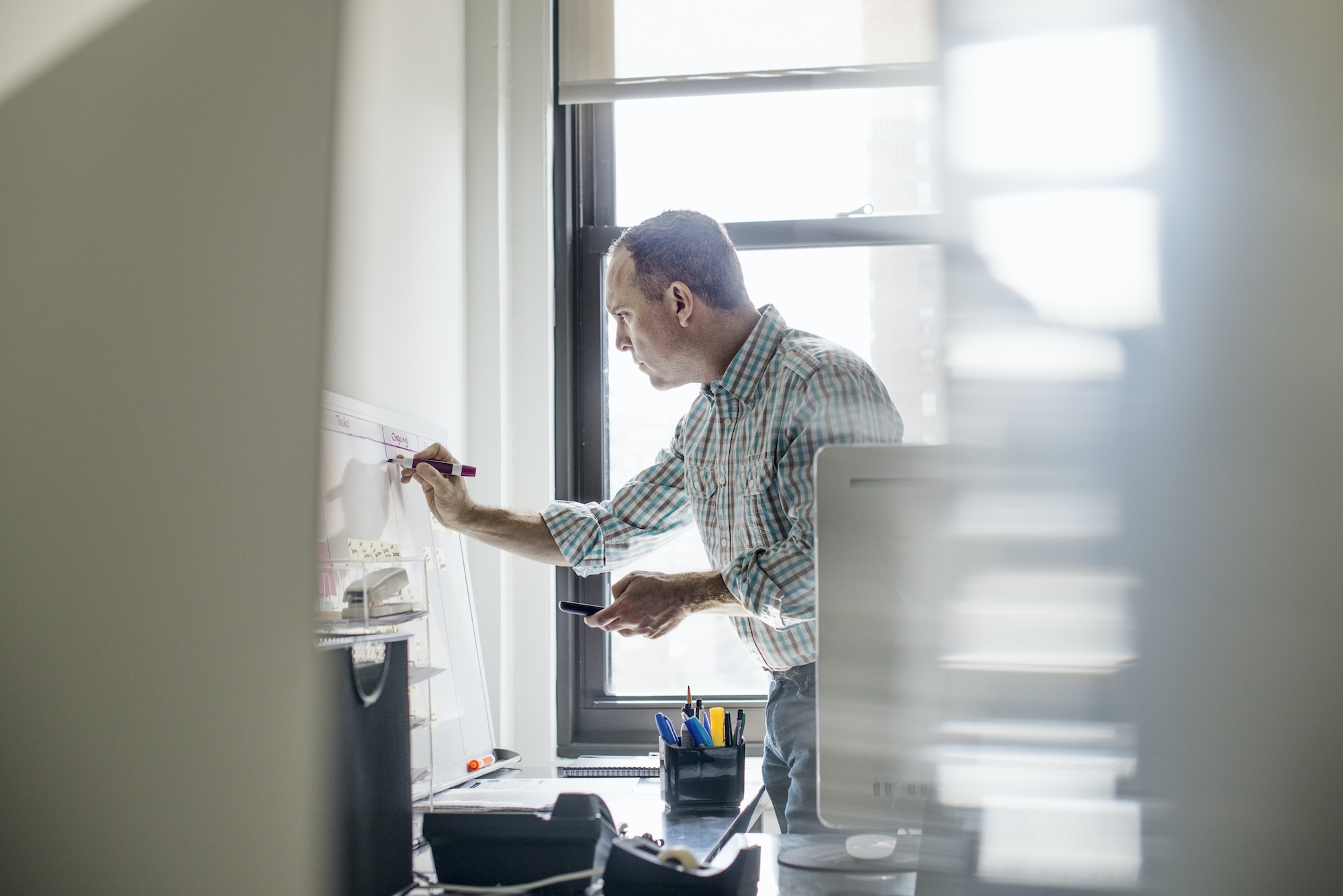 office life a man standing up working and making notes on a wall chart project management