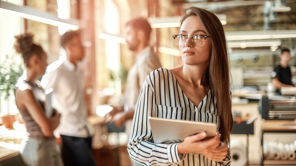 Smart and confident. Young woman in eyeglasses holding digital tablet and looking at camera while